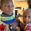 Ngirethi  holds her younger sister, Mary, as they wait to be screened for malnutrition at Sasame Dispensary.