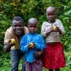 Father stands with two children on their farm, holding lemons