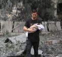 Man holding child amongst rubble and debris in Gaza