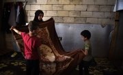 Syrian refugee *Dibeh, folds blankets with her sons which have been donated by Concern. Photo: Mary Turner
