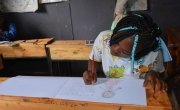 Sheila from Kenya in class drawing what she wants to be when she grows up.