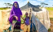 Sori with her son Abudho in Kalacha, Marsabit, standing outside their kitchen garden full surrounded by desert. This season the harvest will include butternut squash, watermelon and spinach. Photo: Jennifer Nolan / Concern Worldwide