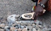 Lucy uses a hammer and flip-flop with a hole in it to break rocks.