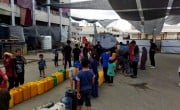 People queuing with water containers at a water truck in North Gaza