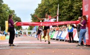 A runner crosses the finish line for the Cardiff Half Marathon, breaking the tape as the first runner across the line. The tape, which is red, reads ‘Principality of Building Society – Cardiff Half’