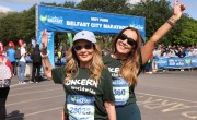 Two women wearing Concern Worldwide shirts and race medals smile for a photo after finishing the Belfast City Marathon 8 Mile Walk, with race bibs and event branding visible.