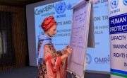 A woman writes on a large paper board.