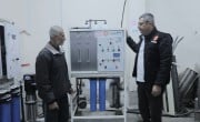 Two men in front of a water filter system