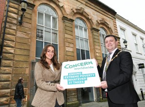 A woman and man holding a board outside an historic building
