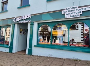 Concern Worldwide charity shop storefront with teal trim and “Ending extreme poverty whatever it takes” sign above windows.