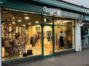 Concern Worldwide shopfront with green exterior, large display windows, mannequins, and lit interior clothing displays.
