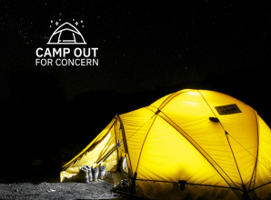 A yellow tent is lit under a dark night sky. A white Camp Out for Concern logo features in the corner.