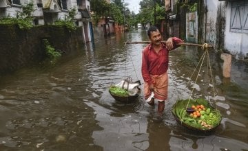 An Indian vegetable vendor carries his wares through floodwaters in Siliguri, West Bengal. Photo: AFP/Diptendu Dutta, 2016