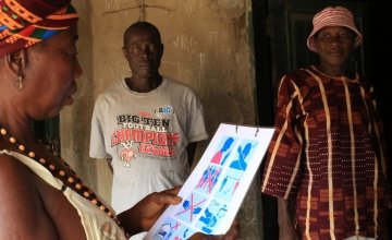A resident looks at a Covid-19 poster distributed by Concern after an awareness session. Photo: Mohamed Saidu Bah
