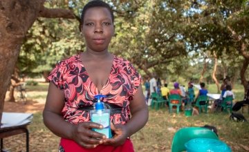 Getruide, a community Health Volunteer in Malawi, holds a hand sanitiser