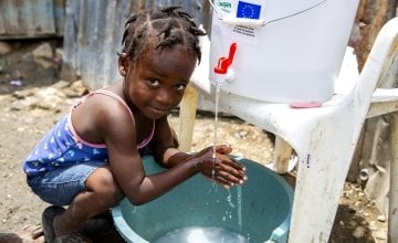 Cherica, two, washes her hands in Haiti