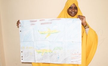 Fatuma from Somalia pictured with her artwork of what she wants to be when she grows up.