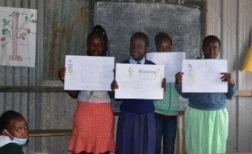 The class of a primary school in Kenya holding up their drawings of their hopes and ambitions.