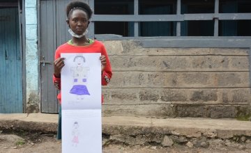 Jane from Kenya pictured holding her drawing of what she wants to be when she grows up.