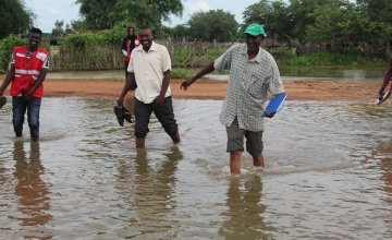 A Concern aid worker walking through flood water in Sudan