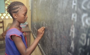 A student in class 1 at Benevolent Islamic Primary School in Makinth community in Sierra Leone writes on the black board, 2015. Photo: Michael Duff / Concern Worldwide.
