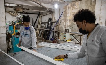 Two Ethiopian apprentices in a workshop, measuring a frame