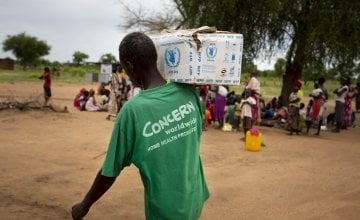 A man in a Concern vest carries supplies at a nutrition clinic in South Sudan