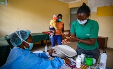 Jane Wanjiru has brought her baby son Mark Moses (11 months old) to Mukuru Health Centre. Facility staff Damaris Too (green t-shirt) and Nutritionist Angela Mtiini (wearing gown) assess Mark Moses Photo: Ed Ram / Concern Worldwide