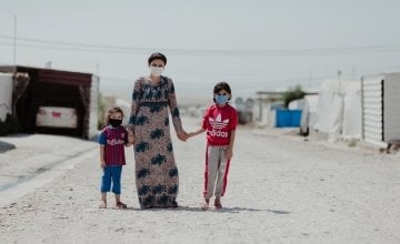 Sheren stands in the street outside their tent with her two daughters in Khanke camp. Photo: George Henton
