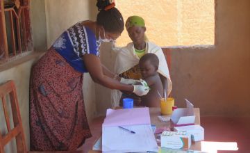 A community health worker checks a child for malnutrition using a MUAC band