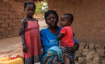 Caustasie, 61, and her grandchildren Gloria, 4, and Emmanuel, 1 year 8 months old in Kiambi, Manono Territory.