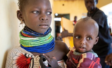 Ngirethi  holds her younger sister, Mary, as they wait to be screened for malnutrition at Sasame Dispensary.