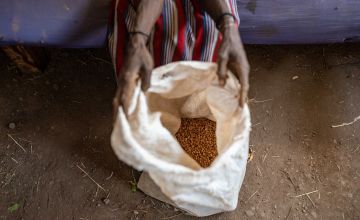 A Kenyan woman holding open a bag of grain