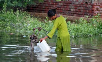 A woman filling a container with drinking water in Sindh after flooding devastated large parts of Pakistan.