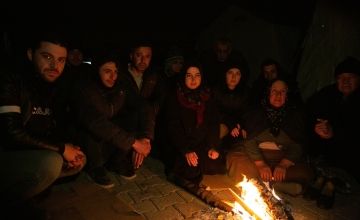 Mehmet (3rd from left) and members of his family stay warm outside a tent which has become their temporary home in Adiyaman, Türkiye. Photo: Kieran McConville/Concern Worldwide