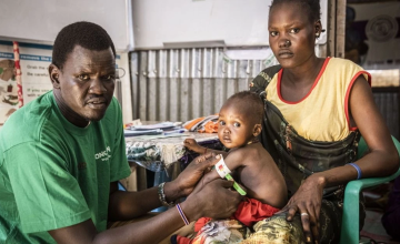 Nyahok Diew with her daughter, Nyariek. The Concern health care worker is using a special band to evaluate Nyariek's level of malnourishment. Photo: Ed Ram/Concern Worldwide