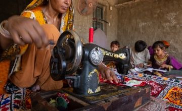 Nusrat uses her sewing machine to stitch a shirt in the family home, as a source of additional income. Her husband is a farmer and was badly impacted by the 2022 floods in Sindh, Pakistan.