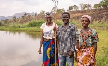A man and two women stand beside a dam
