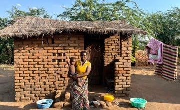 Eliza holds her baby outside her home in Bitilinyu camp