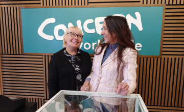 Two women smile at each other in a Concern shop