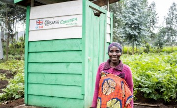 A programme participant stands in front of a latrine built by Concern as part of the SAFER project. Photo: Samuel Isenge/Concern Worldwide
