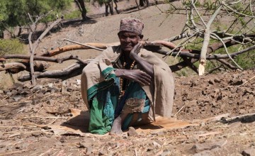 Adina sits on a mat in the compound of her household. During the dry season, she sleeps outside on this mat due to the limited space inside the house. Photo: Eugene Ikua/Concern Worldwide.