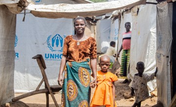 A woman stands with her child in a displacement camp.