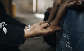 An adult woman's hands hold small child legs at a health centre