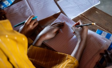 Two students write in workbooks.