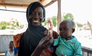 A mum with her son holding a sachet of therapeutic food