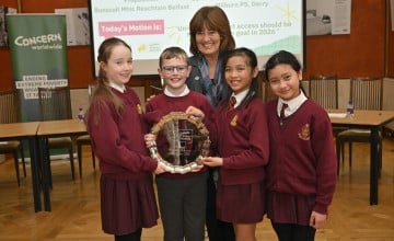 Students in red uniforms stand in Stormont holding awards