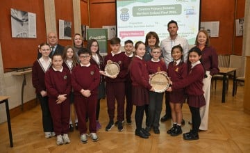 Students in red uniforms stand in Stormont holding awards