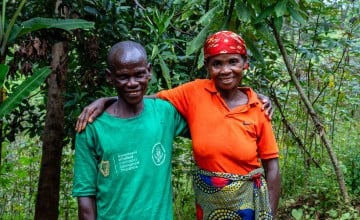 A couple stands with their arms around one another