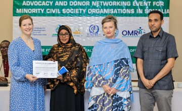 A woman is presented with a certificate while three other people stand beside her.